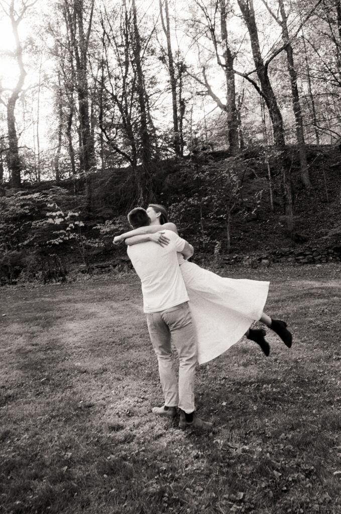man spinning woman in white dress while smiling and giggling during film engagement photos