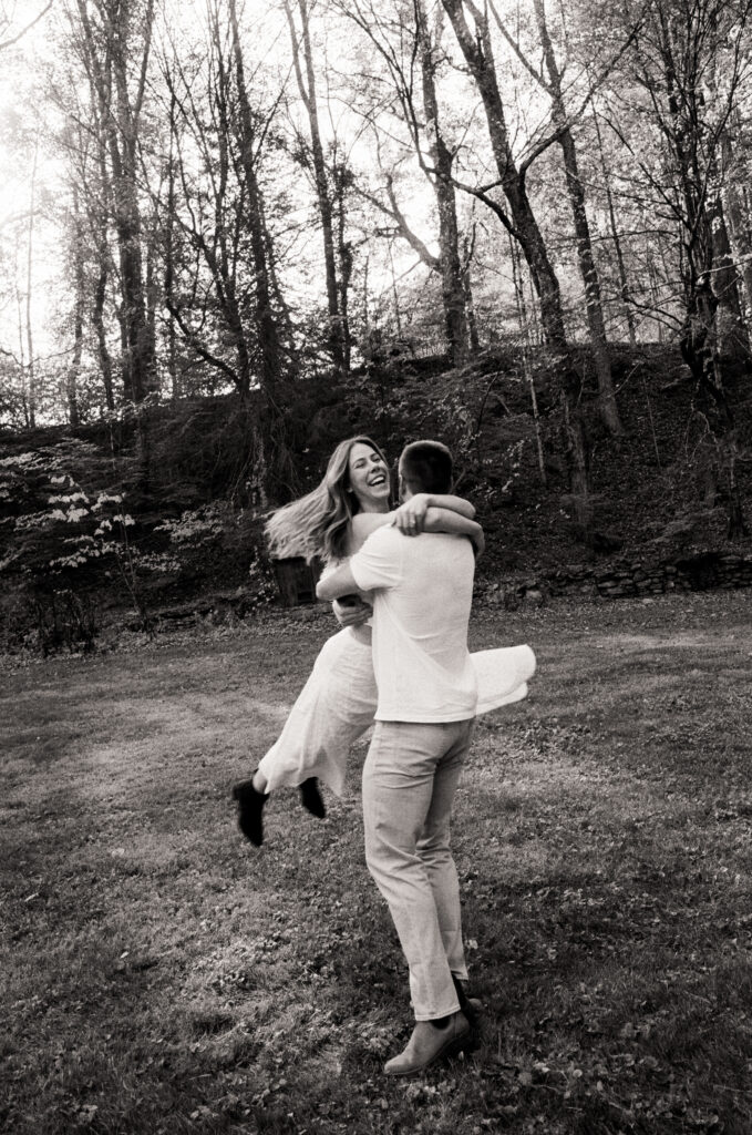 man spinning woman in white dress while smiling and giggling during film engagement photos