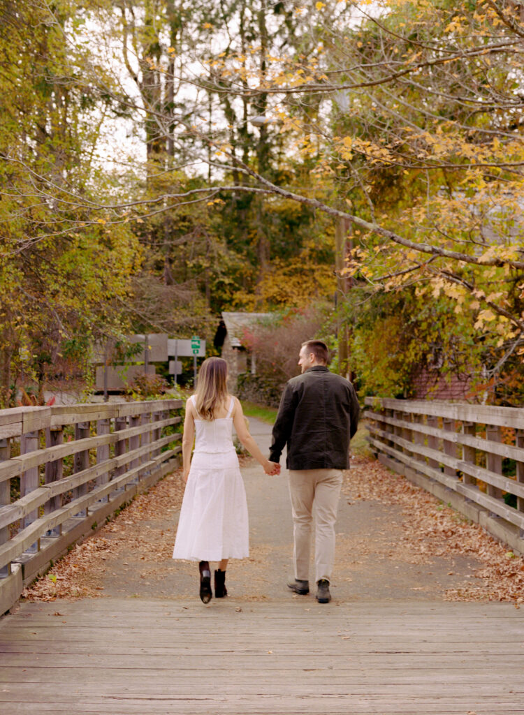 couple smiling lovingly at each other on bridge during fall