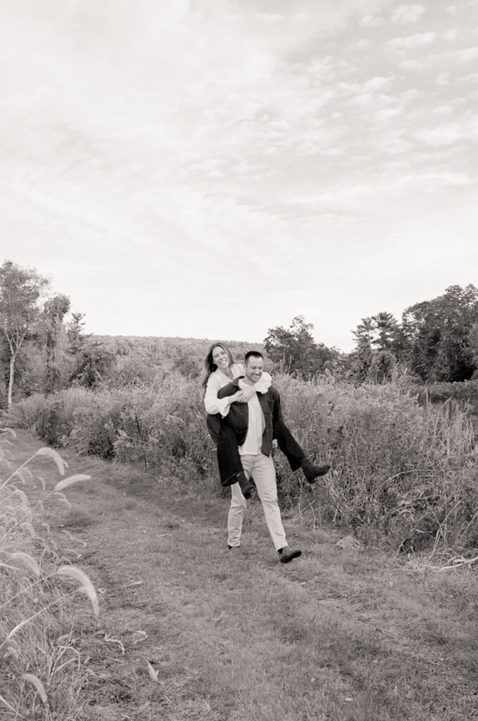 man giving a woman a piggy back ride in a field 
