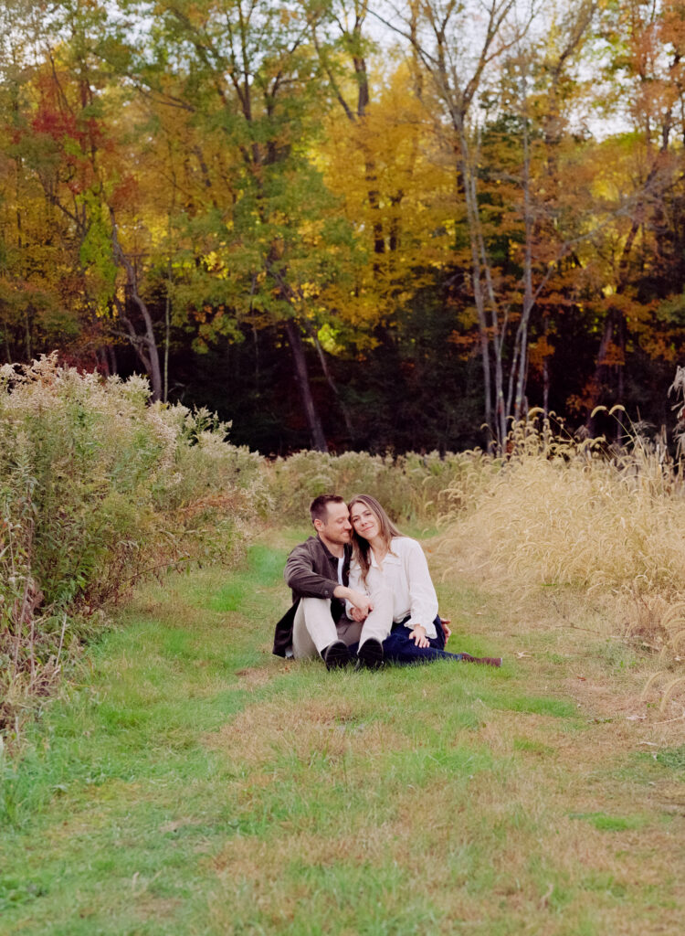 couple snuggling in a field during film engagement photos 