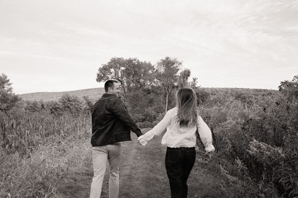 black and white photo of couple running in a field during a film engagement photos 