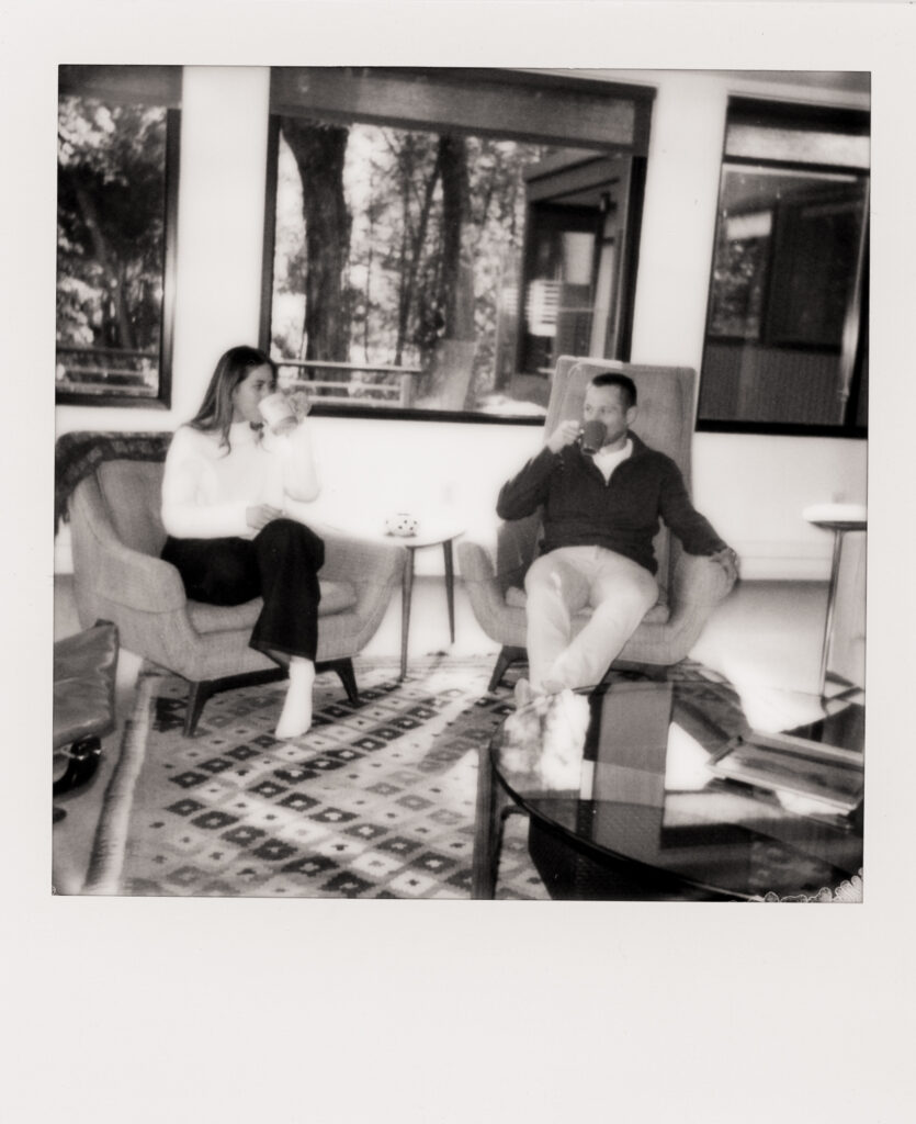 polaroid photo of couple sitting drinking coffee and looking lovingly at each other 