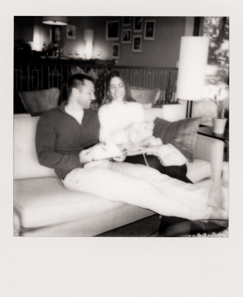 polaroid photo of couple sitting on couch knitting and reading 