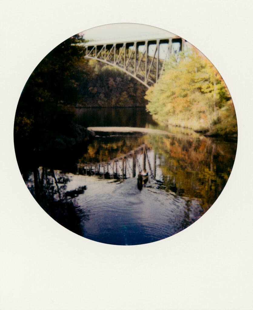 film photo of couple canoeing under bridge during fall 