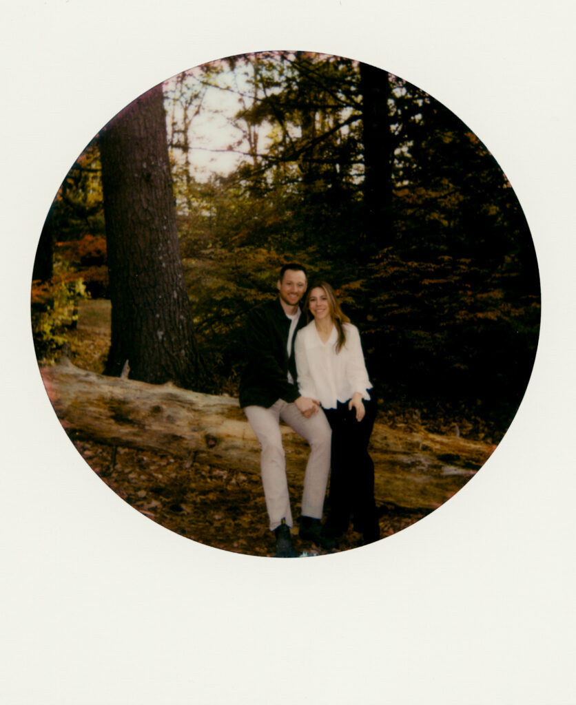 polaroid of couple sitting on fallen tree in the woods during film engagement photos 