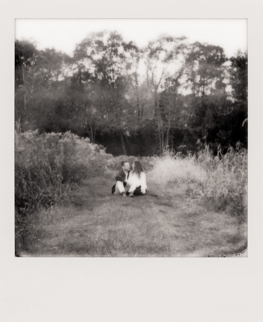polaroid photo of couple snuggling in a field during film engagement photos 