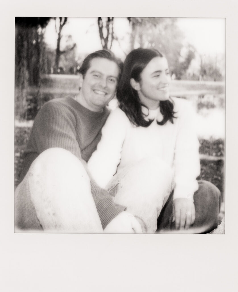 couple smiling under a tree during film engagement photos 