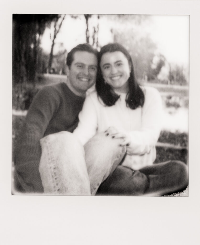 couple smiling under a tree during film engagement photos 