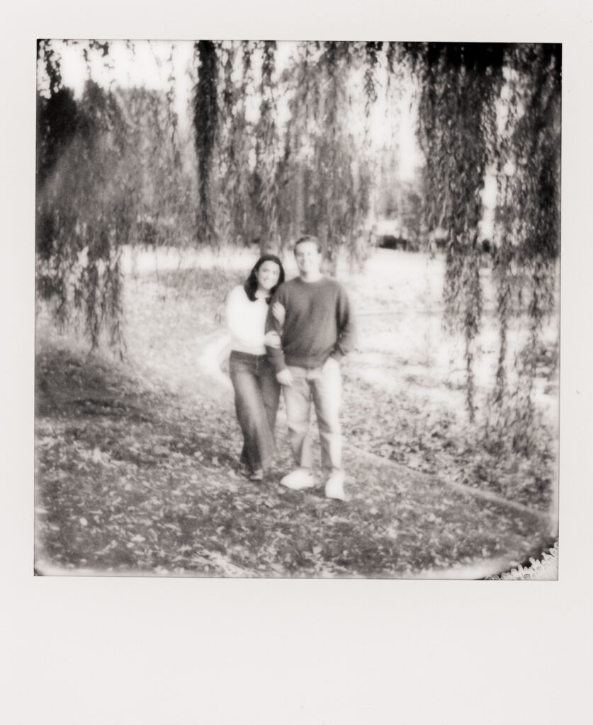 couple smiling under a tree during film engagement photos 