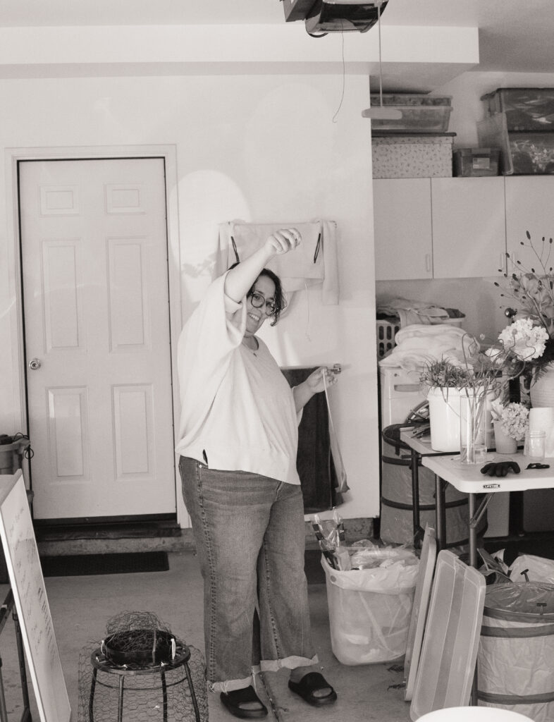 a woman standing in a room working on wedding flowers 