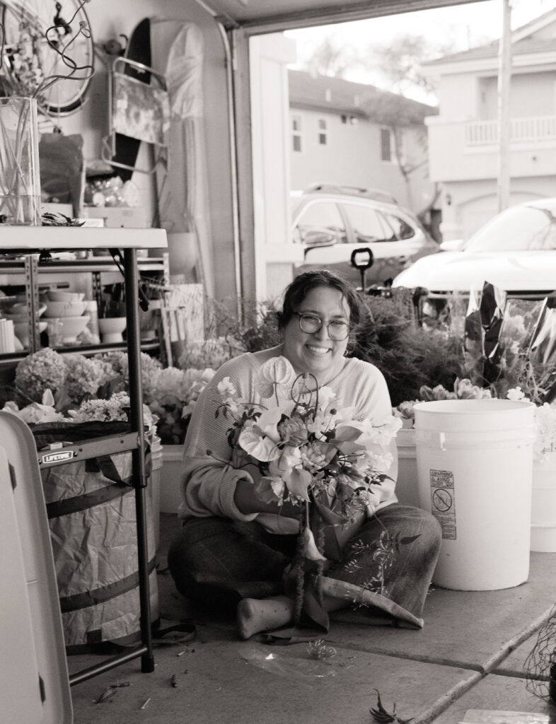 a woman sitting on the ground holding flowers