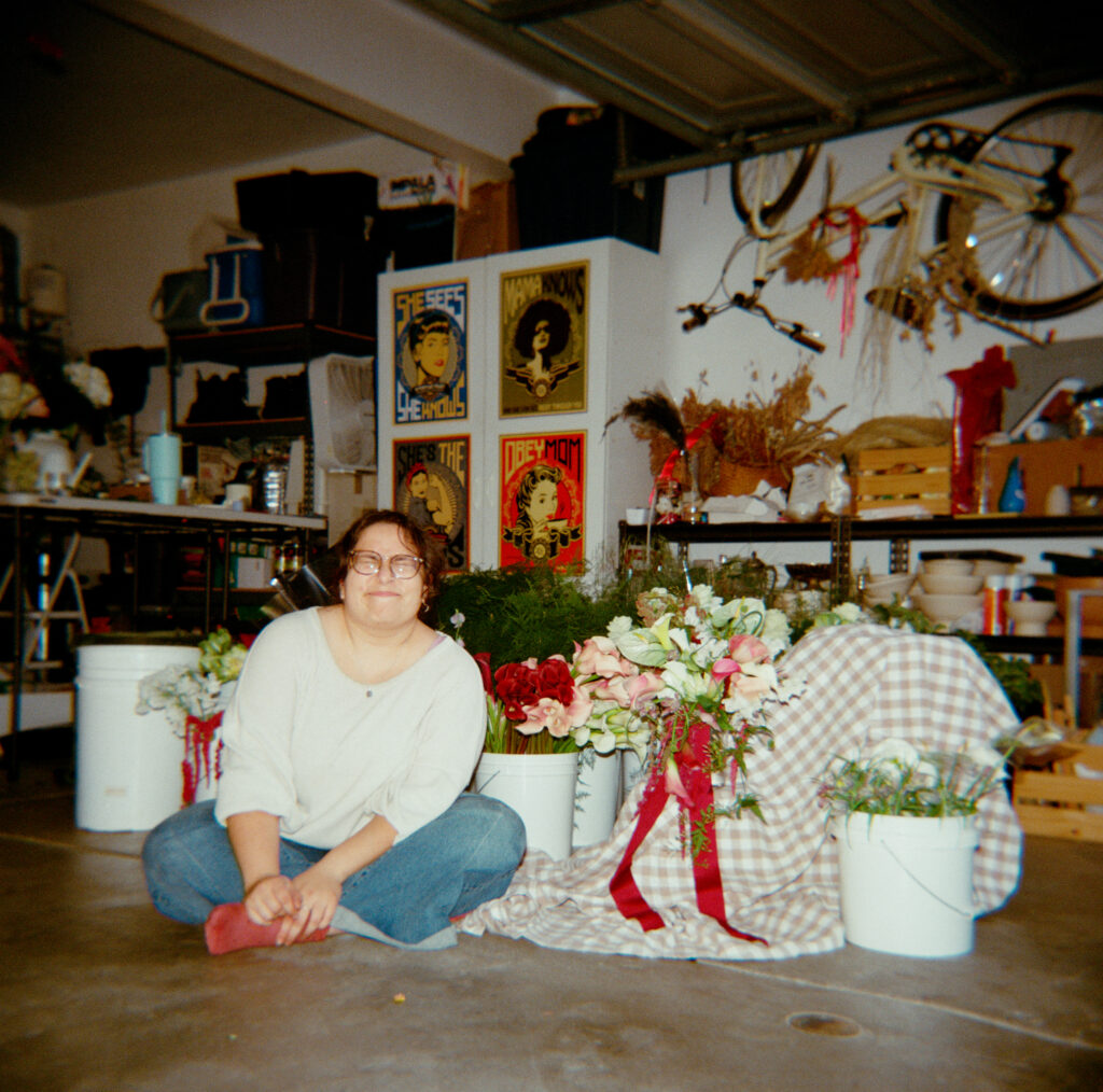 a woman sitting on the floor in a garage with flowers