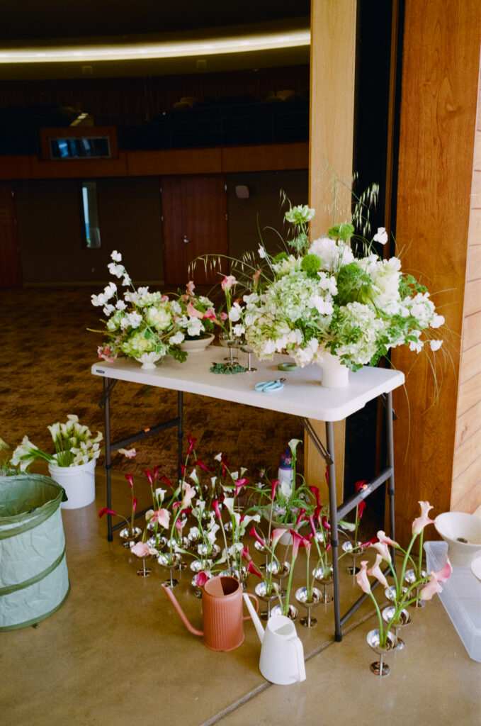 a group of flowers in small glasses and a white table with larger flowers on it 