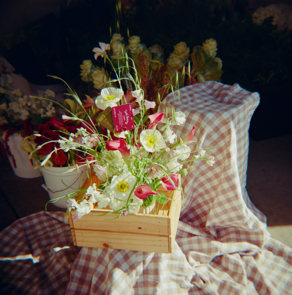 organic floral arrangement sitting in a wood box on a gingham sheet for a Scripps Seaside Forum wedding 