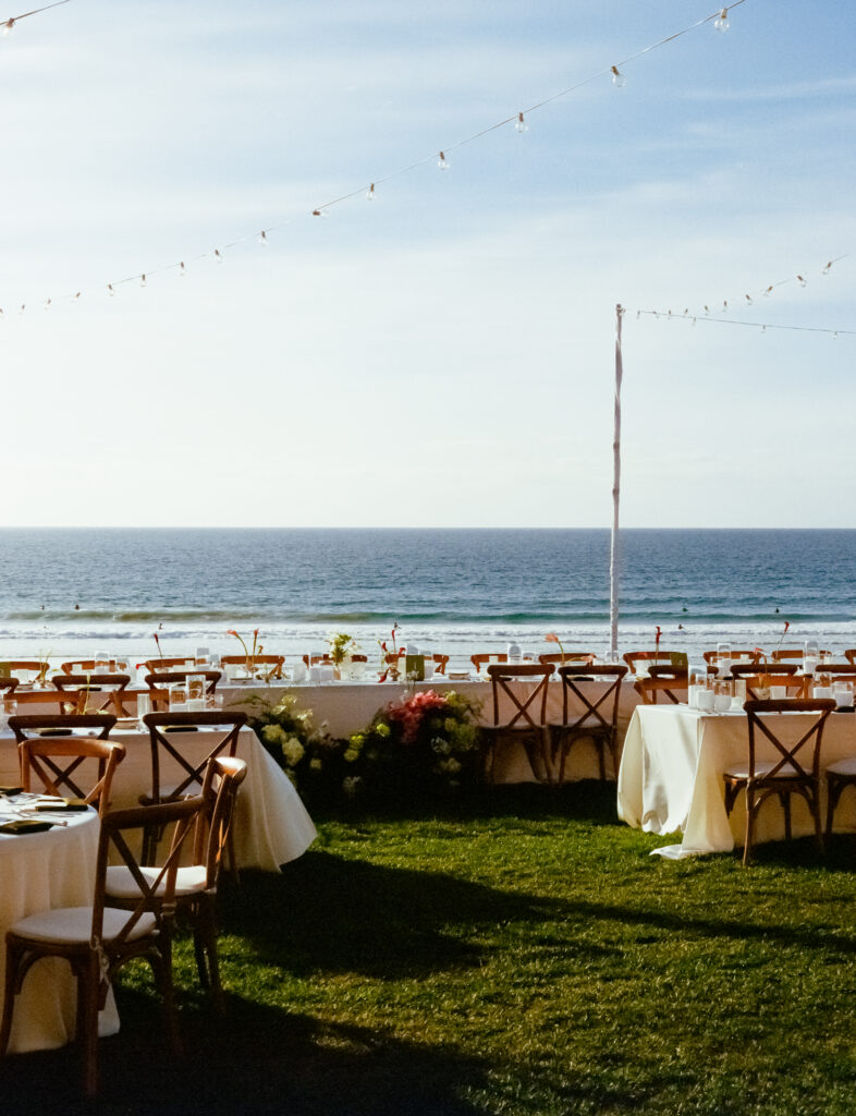 wedding tables, flowers, and string lights on the beach