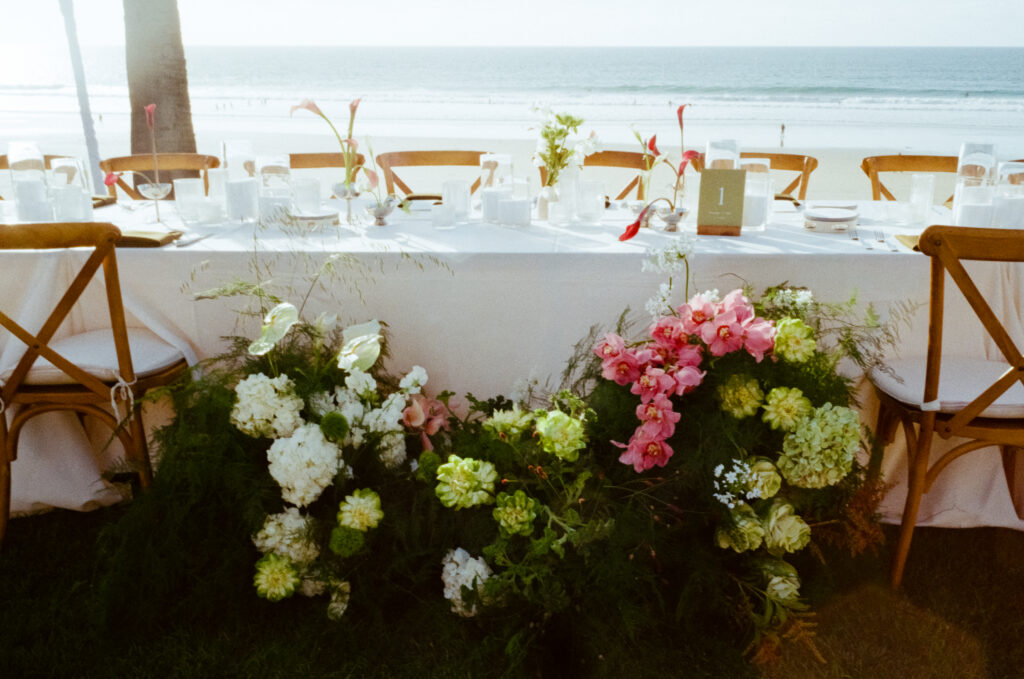 wedding tables, flowers, and string lights on the beach