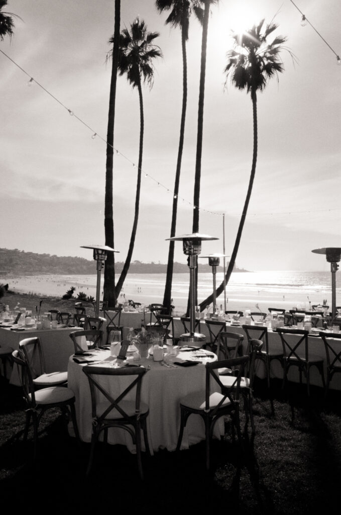 wedding tables, flowers, and string lights with palm trees and the beach in the back ground 