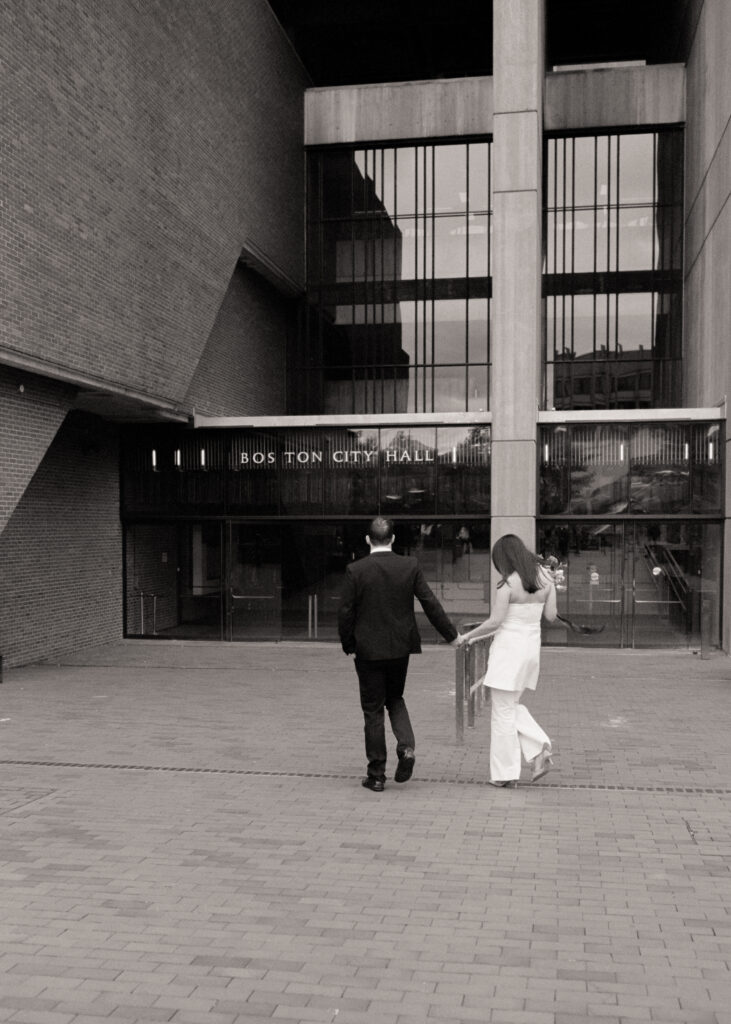 man and woman holding hands walking into the Boston City Hall for their elopement 