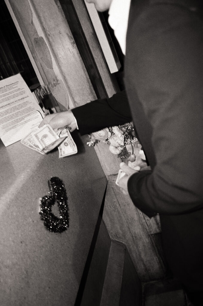 man handing money at a desk to pay for a Boston City Hall elopement in black and white photo