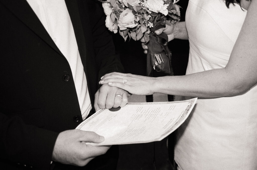 woman grabbing a mans hand that is holding their wedding certificate 