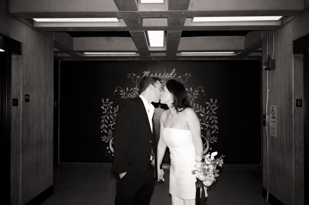 newly married couple kissing in front of a just married sign at the Boston City Hall 