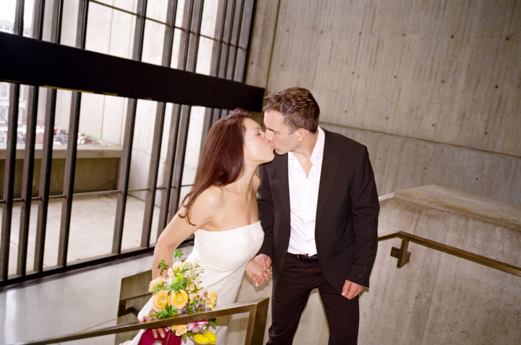 man and woman holding hands and kissing after their Boston City Hall elopement 