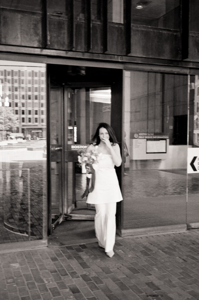 Woman walking out of city hall holding a wedding bouquet after eloping 