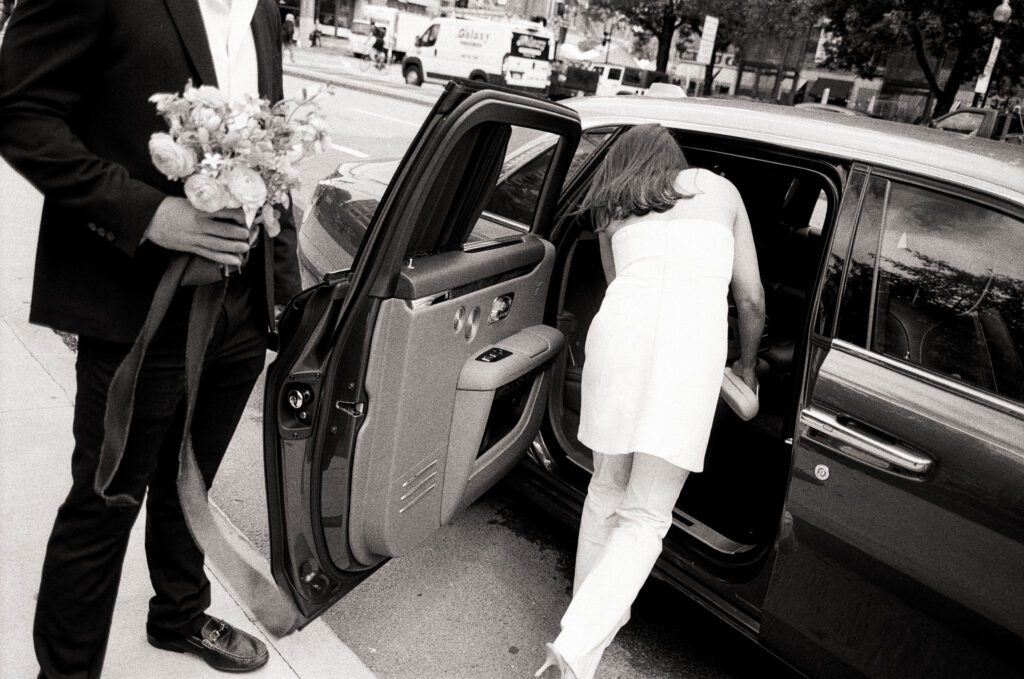 groom holding the door open for his bride as they leave the Boston City Hall after their elopement 