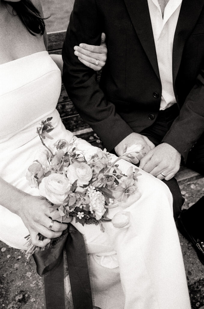 woman holding a bridal bouquet with her other arm around her husband in black and white photo 