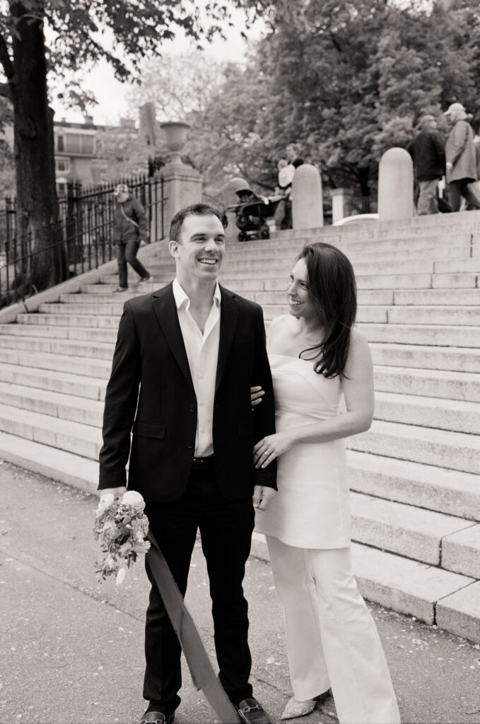 bride and groom posing in front of steps in a black and white photo 