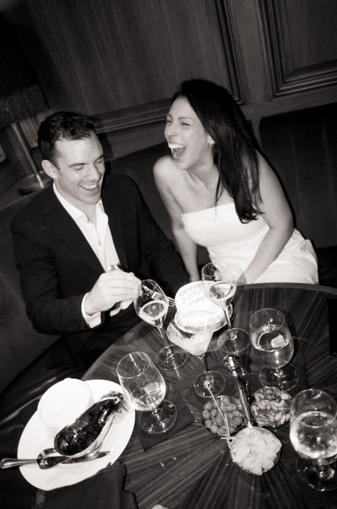 newly married couple having champagne and eating cake in a booth during dinner after their Boston City Hall elopement 