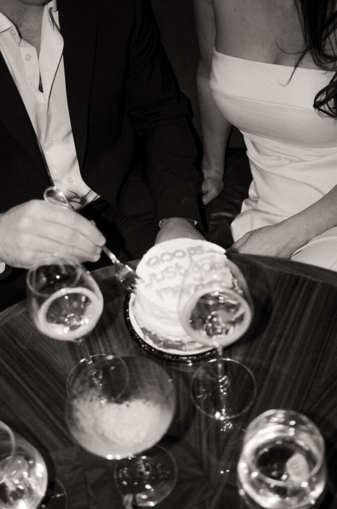 newly married couple having champagne and eating cake in a booth during dinner after their Boston City Hall elopement 