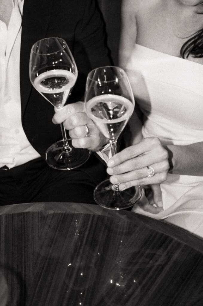 newly married couple having champagne and eating cake in a booth during dinner after their Boston City Hall elopement 