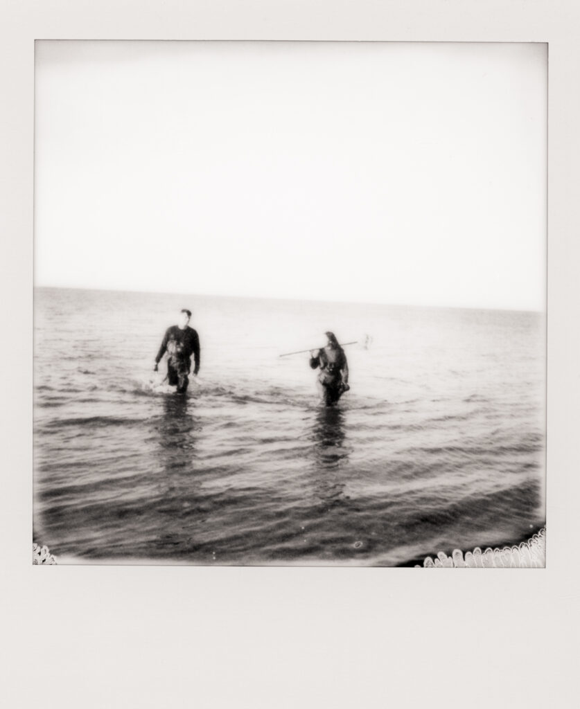 man and women walking out of ocean after clamming during a Cape Cod engagement photos in polaroid photo