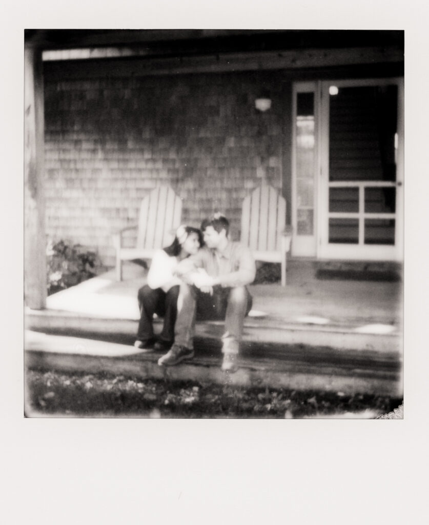 polaroid photo of couple hugging on porch in front of house during film engagement photos in Cape Cod