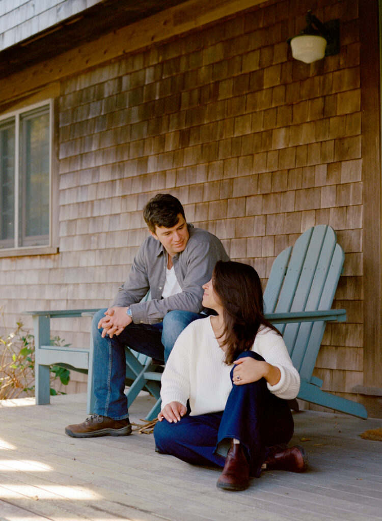man sitting on a porch chair and looking down at a woman who sits on the floor near him