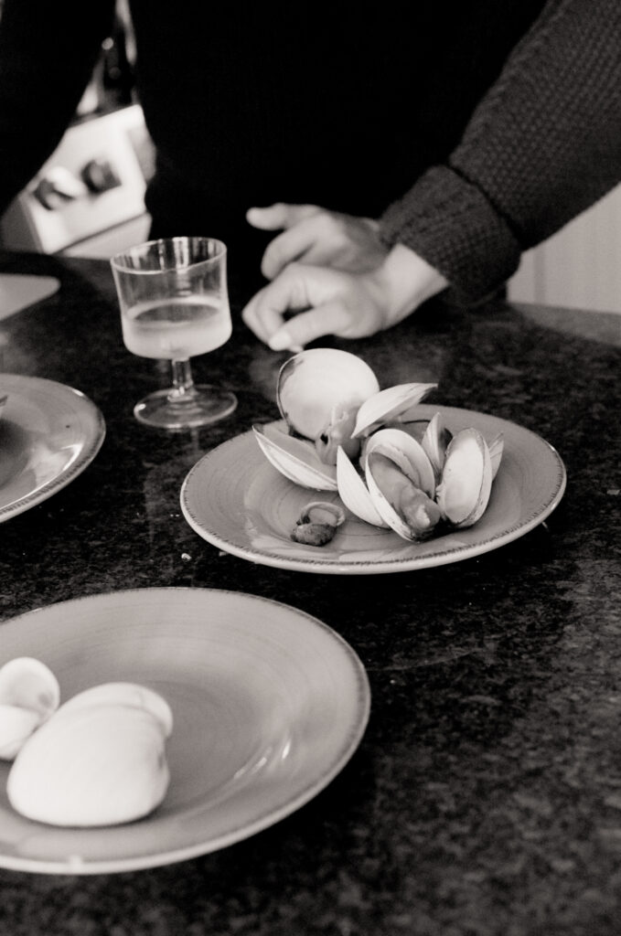 clams on white plate with a glass of white wine