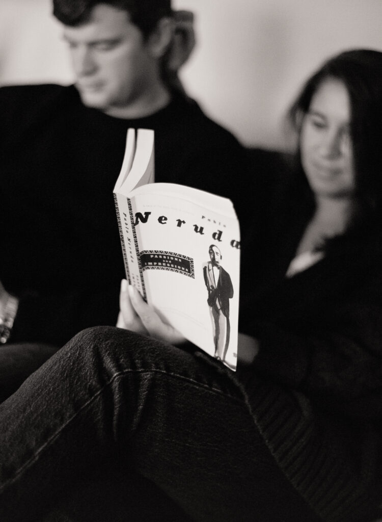 black and white photo of a man and woman sitting together on a couch reading