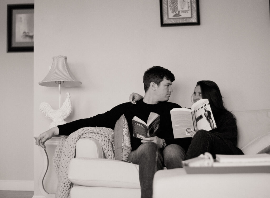 black and white photo of a man and woman sitting together on a couch reading