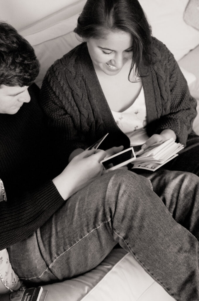 black and white photo of couple looking and smiling at polaroid photos