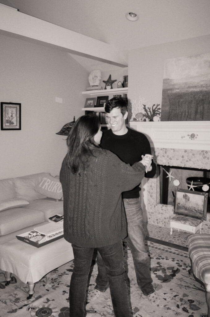 black and white photo of couple dancing in living room during film engagement photos in Cape Cod