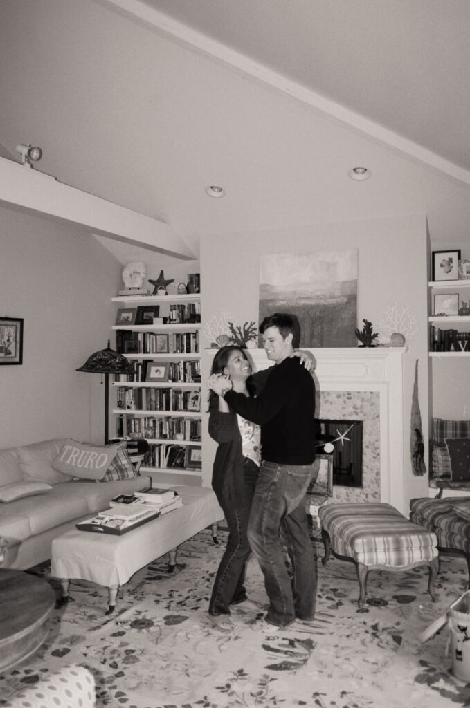 black and white photo of couple dancing in living room during film engagement photos in Cape Cod